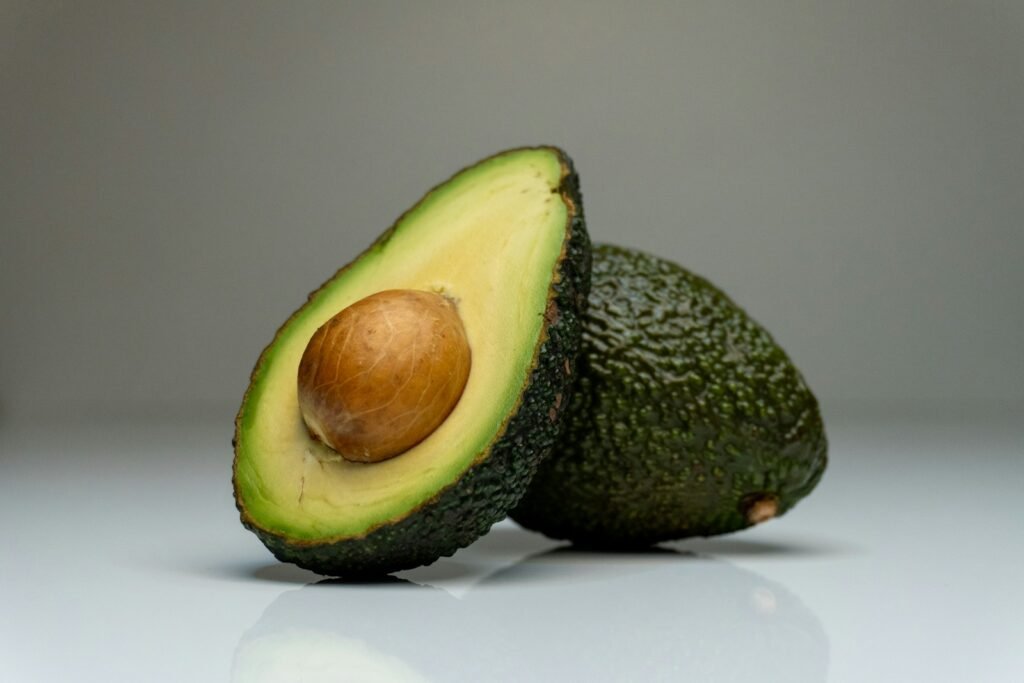 an avocado cut in half on a white surface